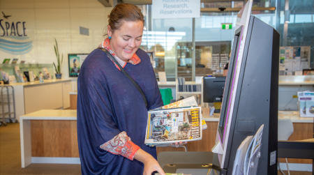 Gemma borrowing books at self serve counter at Library